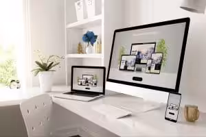 A lap top, pc screen and phone on a desk.
